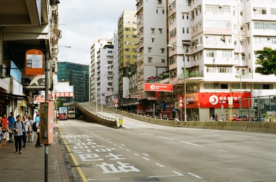 白天，灰色水泥路旁的白色和红色水泥建筑